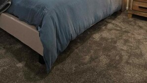 Una camera da letto con un letto, una testiera, un comodino e un quadro appeso al muro.