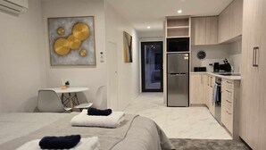 A modern hotel room with two beds, a small dining table, a kitchen area, and a living space. - Bath Street Apartments 6 (Christchurch)