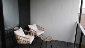 A balcony with wicker chairs and a small round table.