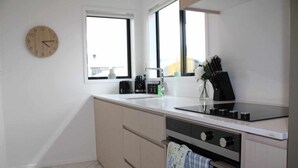 A modern kitchen with a sink, stove, and a clock on the wall.