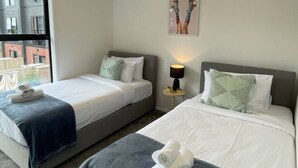 Ein Hotelzimmer mit zwei Betten, einem großen Fenster und Blick auf die Stadt.