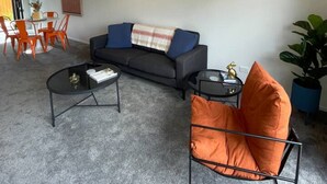 Ein modernes Wohnzimmer mit einer Couch, einem Couchtisch und einem orangefarbenen Sessel.