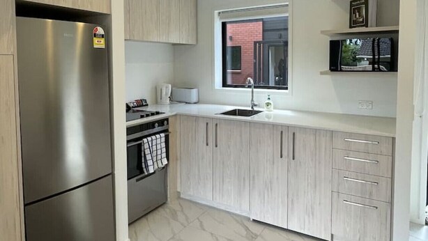A modern kitchen with a stainless steel refrigerator, a built-in oven, and a microwave.