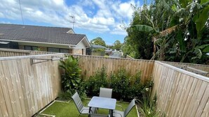 A backyard with a wooden deck, a small table with chairs, and a grassy area.