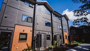 Un immeuble moderne à plusieurs étages, doté d’une façade en briques et de grandes fenêtres.