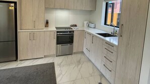 Une cuisine moderne avec des meubles en bois clair, des appareils en acier inoxydable et un sol en marbre.