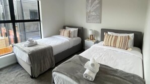 Une chambre d’hôtel avec deux lits, une grande fenêtre et une vue sur les bâtiments environnants.