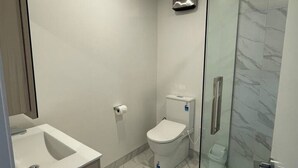 A modern bathroom with a glass-enclosed shower, a toilet, and a sink.