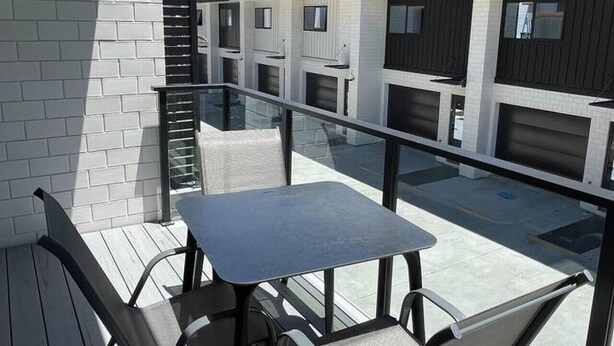 A balcony with a table and chairs, overlooking a building with multiple windows and balconies.