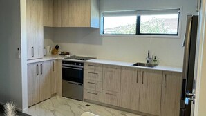 A modern kitchen with light wood cabinets, a built-in oven, and a window above the sink.