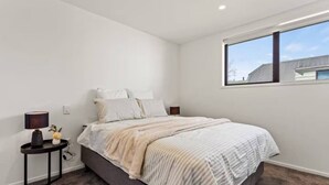 Une chambre à coucher avec un lit, une table de chevet, une lampe et une fenêtre.