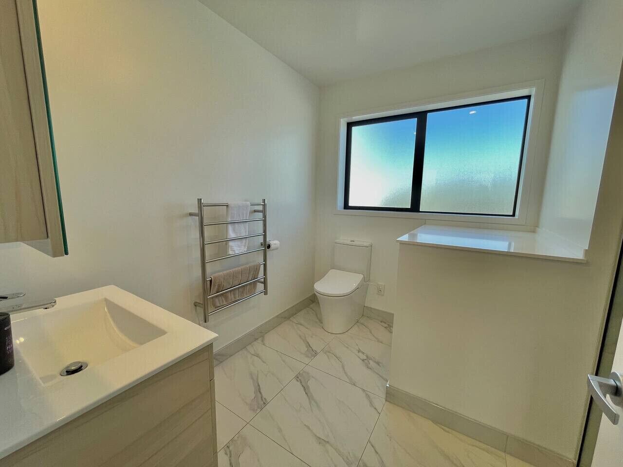 Ein Badezimmer mit Waschbecken, Toilette und Handtuchhalter.