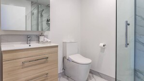 Un bagno moderno con cabina doccia in vetro, un water bianco e un mobile vanità in legno con specchio.