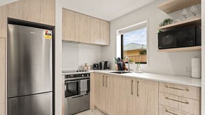 Une cuisine moderne dotée d’appareils électroménagers en acier inoxydable, de meubles en bois et d’une fenêtre offrant une vue sur l’extérieur.