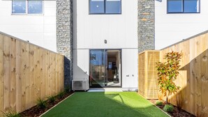 A modern building with a flat roof, white exterior walls, and a central entrance with glass doors.