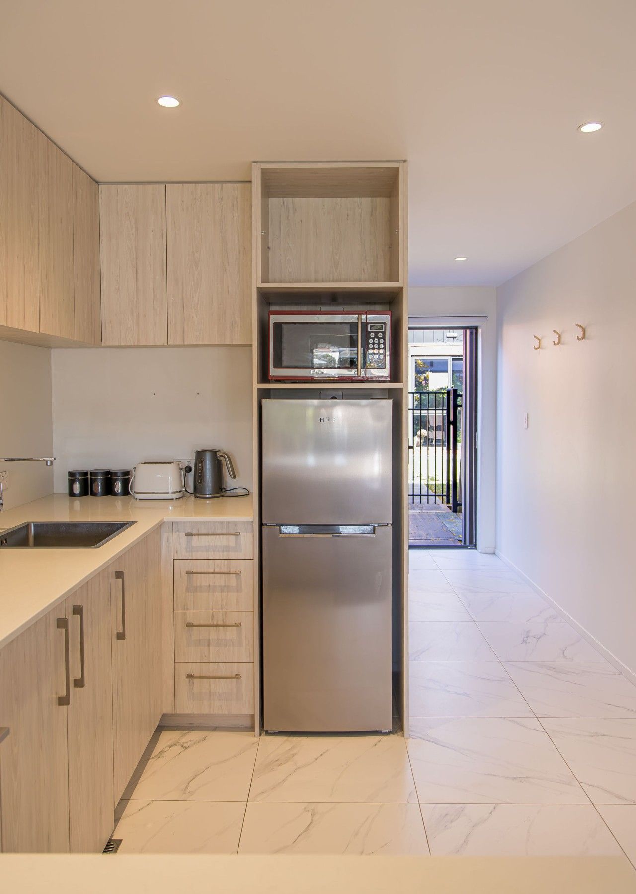 Una cocina moderna con microondas integrado, refrigerador de acero inoxidable y armarios de madera.