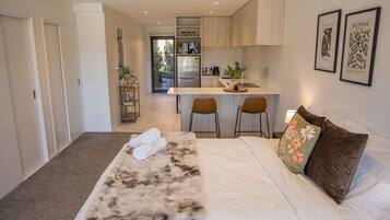 A hotel room with a bed, a small kitchenette, and a view of the outside.