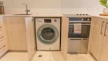 Een praktische keuken met een ingebouwde wasmachine en droger, een spoelbak en een oven.