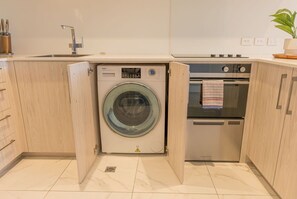 A compact kitchen with a built-in washer and dryer, a sink, and an oven.