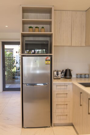 A modern kitchen with a stainless steel refrigerator, wooden cabinets, and a built-in oven.