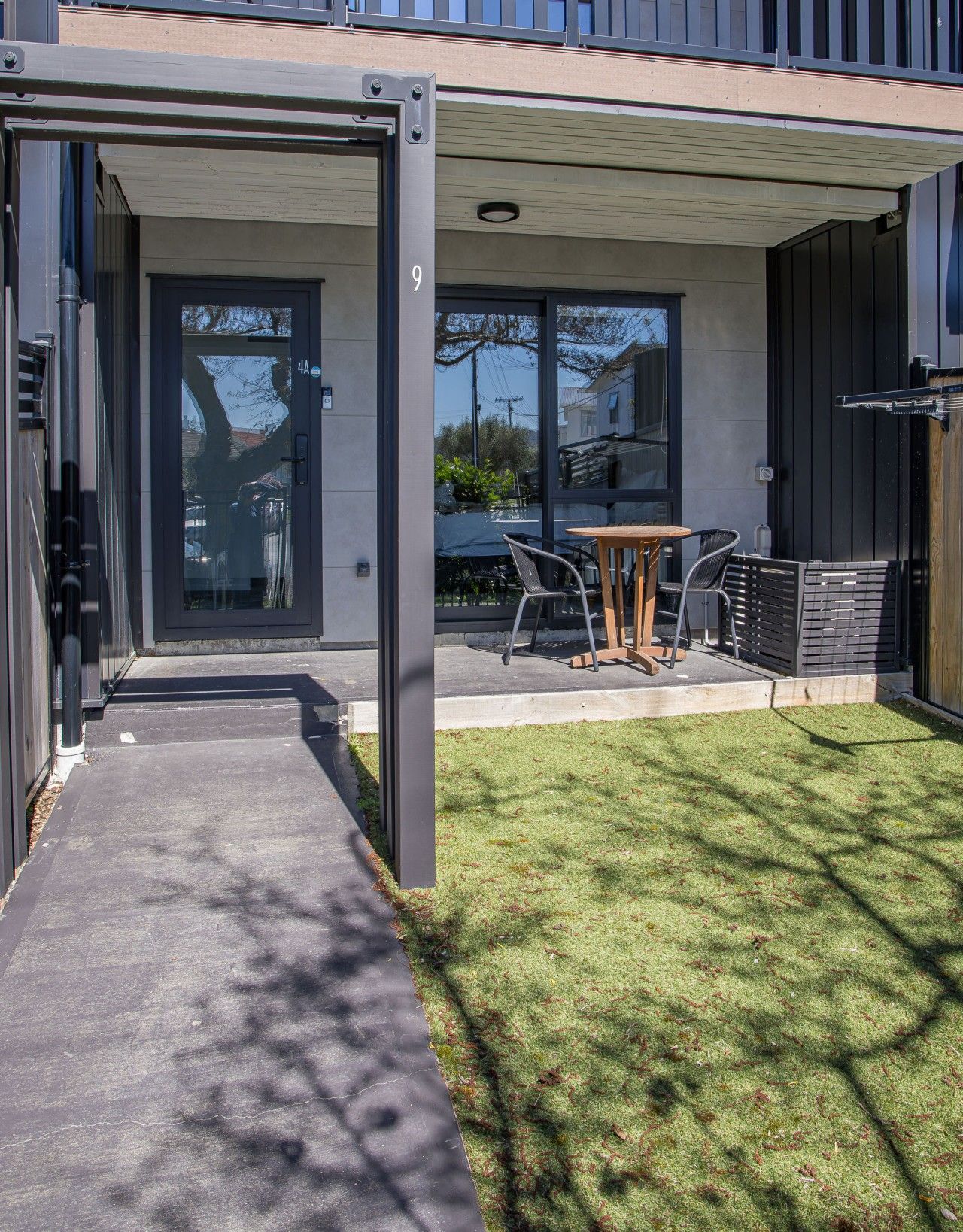 A modern building with a covered patio area, a number 9 sign, and a small table with chairs.