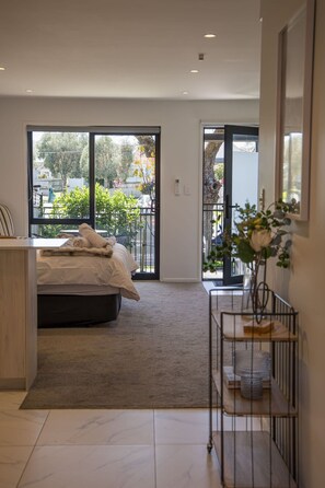 A modern bedroom with a bed, a desk, and a view of the outside.