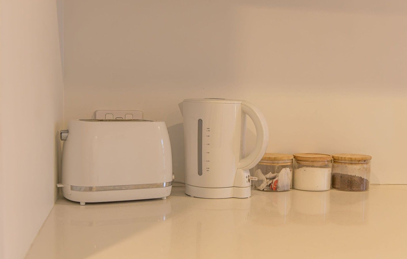 A kitchen counter with a toaster, a coffee maker, and two jars of spices.