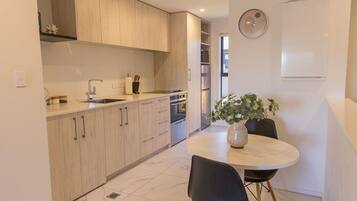 A modern kitchen with wooden cabinets, a dining table with chairs, and a potted plant.