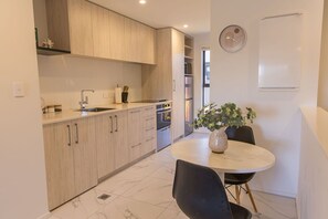 Una cocina moderna con armarios de madera, una mesa de comedor con sillas y una planta en maceta.