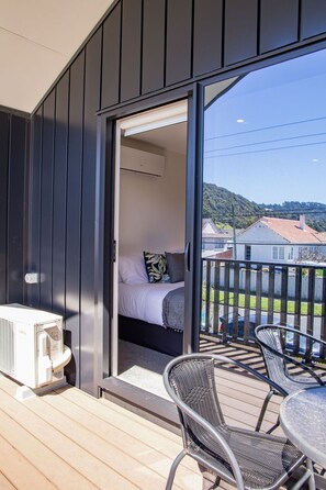 A balcony with a bed, a table, and chairs. - Bright Studio Apartment on Macky Street (Lower Hutt)