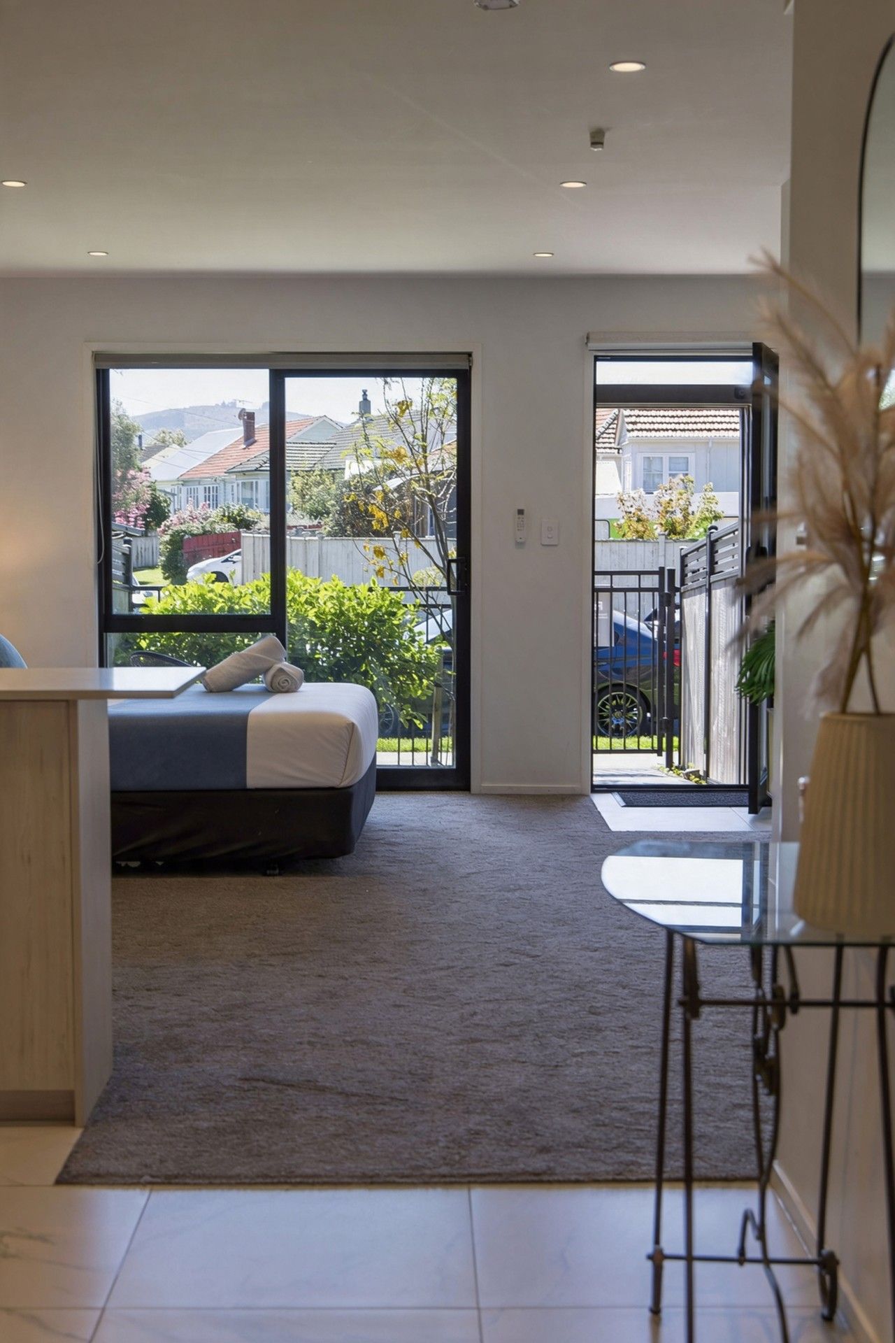 A modern bedroom with a bed, a desk, and a view of the outside.