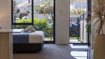 A modern bedroom with a bed, a desk, and a view of the outside.