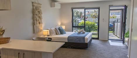 A modern bedroom with a bed, bedside table, and a view of the outdoors through a sliding door.