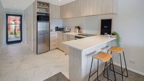 A modern kitchen with a central island, stainless steel appliances, and light wood cabinetry. - Macky Street Studio Retreat (Lower Hutt)