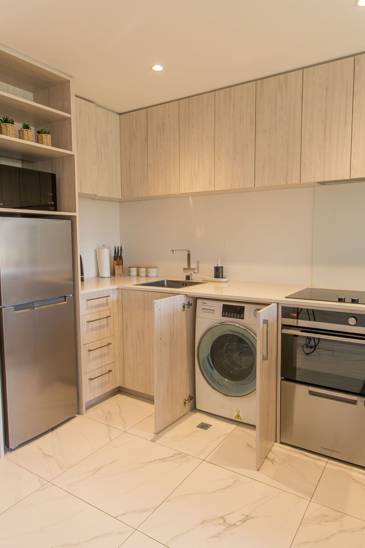 A modern kitchen with a built-in washing machine, a stainless steel refrigerator, and a dishwasher.