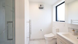 Ein modernes Badezimmer mit Duschkabine aus Glas, Toilette und Waschtisch mit Spiegel.