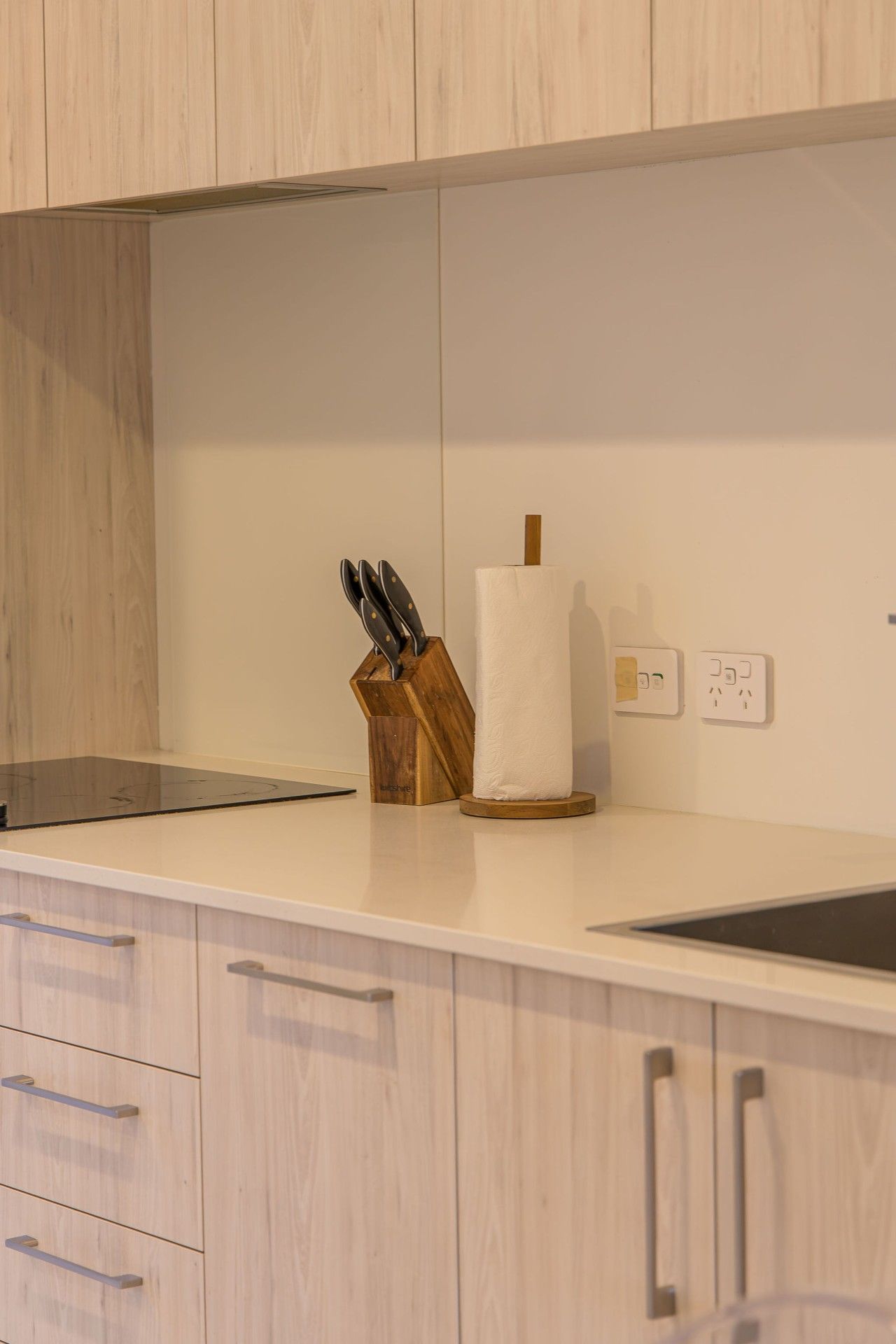 A kitchen with wooden cabinets, a countertop, a knife block, and a paper towel holder.