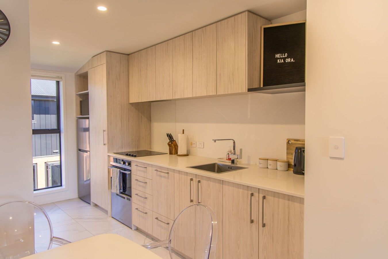 A modern kitchen with wooden cabinets, a stainless steel sink, and a built-in oven.