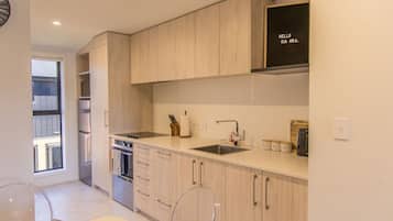 A modern kitchen with wooden cabinets, a stainless steel sink, and a built-in oven.