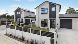 A modern residential building with a garage, a covered patio, and a well-maintained lawn. - Homely Haven in Trentham - 2BR (Upper Hutt)