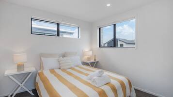 A hotel room with a large bed, two bedside tables, and two windows.
