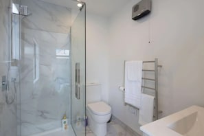 Un baño moderno con ducha de vidrio, inodoro y bañera.