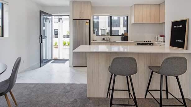 A modern kitchen with a central island, two bar stools, and a welcome sign. - Scenic Views from our 2-BR Trentham Hideaway (Upper Hutt)