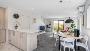 Una cocina moderna con una isla central, un comedor con mesa y sillas, y vistas al exterior.