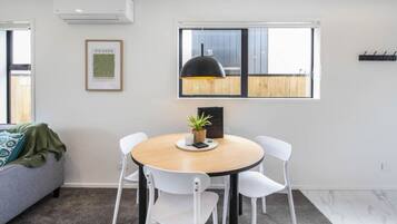 A modern dining area with a round table, white chairs, a black pendant light, and a framed map on the wall.