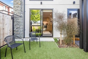 Ein modernes Haus mit Steinaußenwand, ein kleiner Hinterhof mit Rasenteppich und eine Schiebetür zu einer Küche.