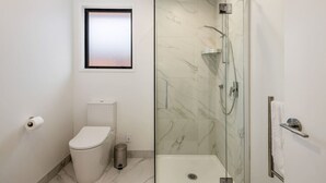 A bathroom with a toilet, a glass-enclosed shower, and a marble floor. - Hutt Hideaway on Milne (Lower Hutt)