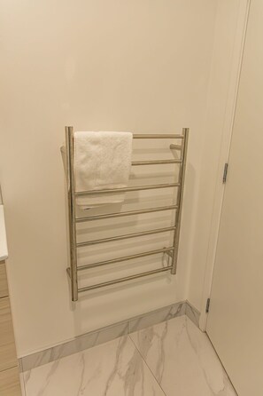 A bathroom with a towel rack against the wall and a door to the right.