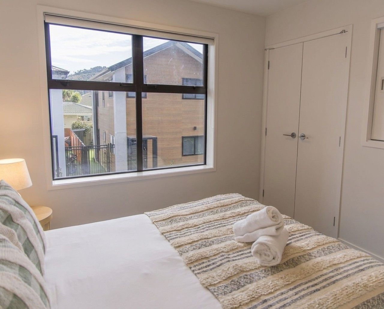 A bedroom with a bed, a window, and a wardrobe.
