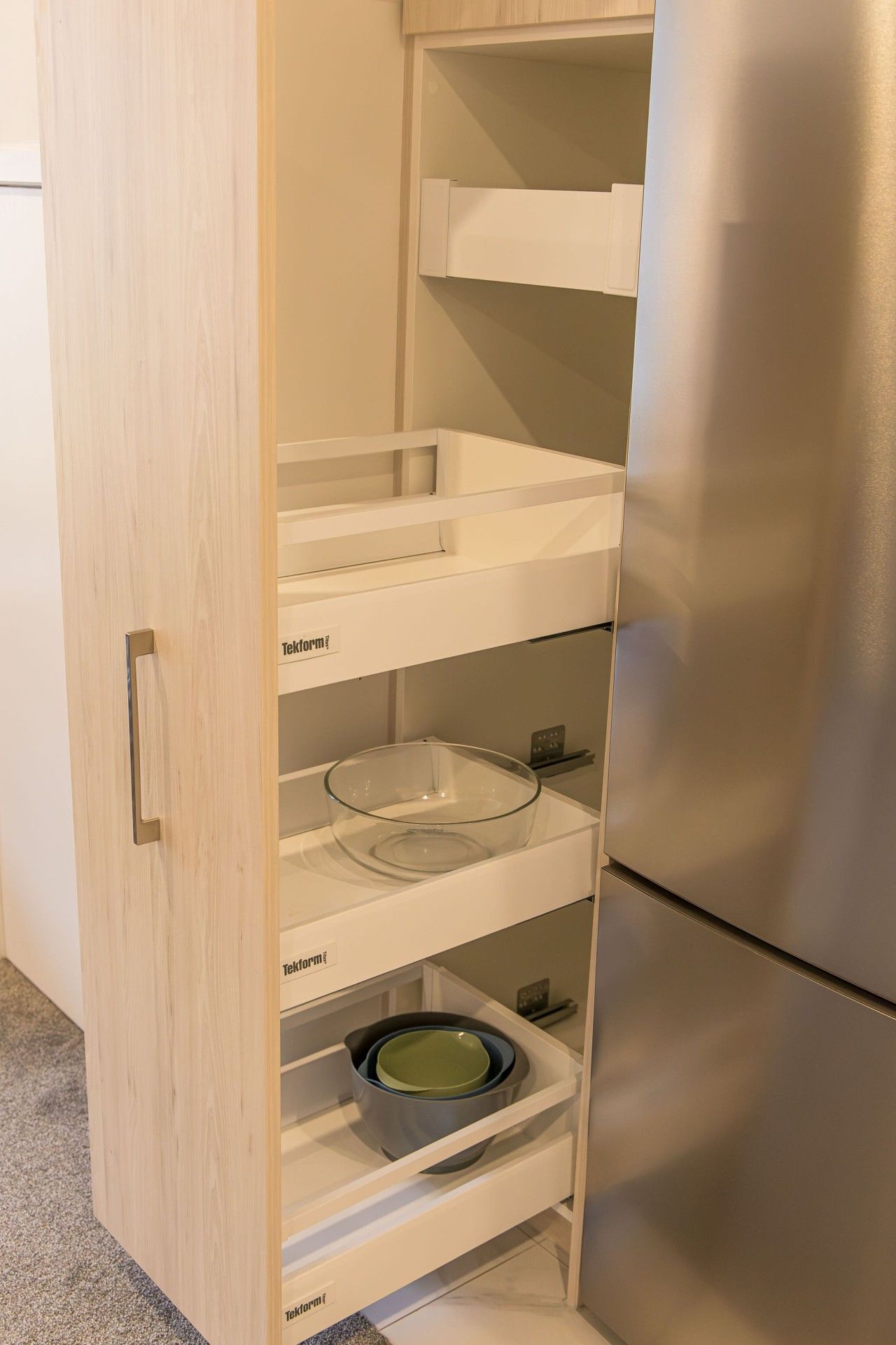 A kitchen with a built-in stainless steel refrigerator and wooden cabinetry.